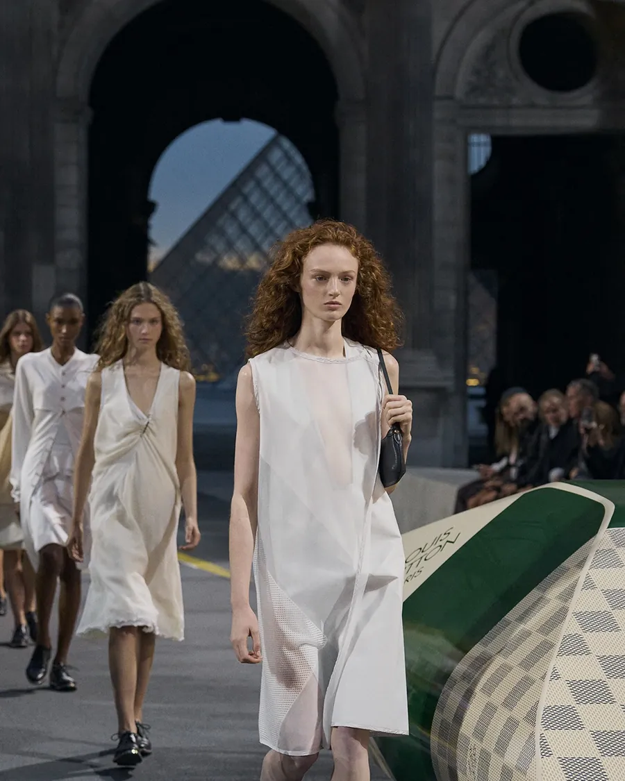 Finale der Schau Louis Vuitton Frühjahr-Sommer 2027: Models in leichten weißen Kleidern in der Cour Carrée, im Hintergrund die Louvre-Pyramide