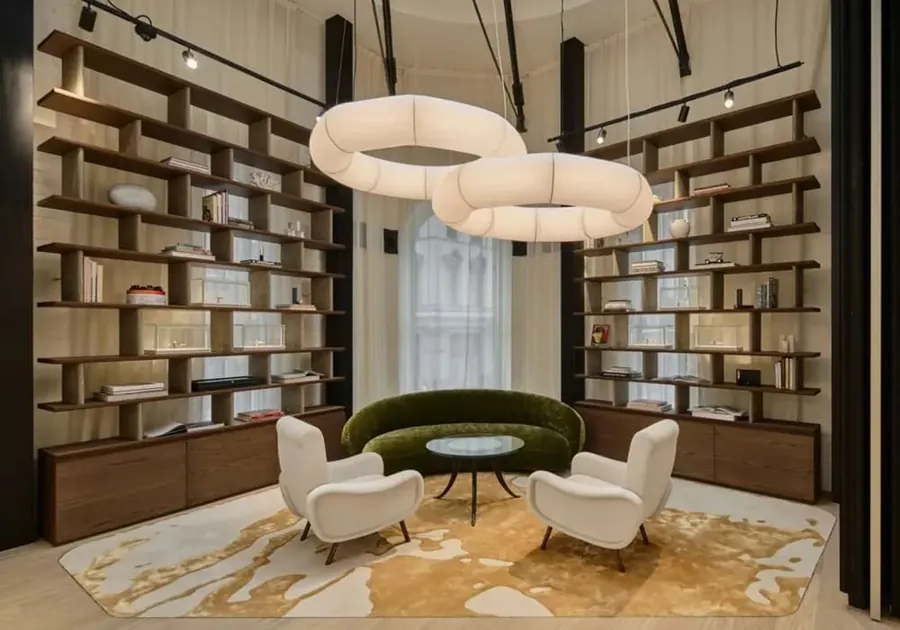 Lounge mit hölzernen Bücherregalen, weißen Sesseln, grünem Sofa und ringförmigen Leuchten in der Montblanc Boutique in Sydney